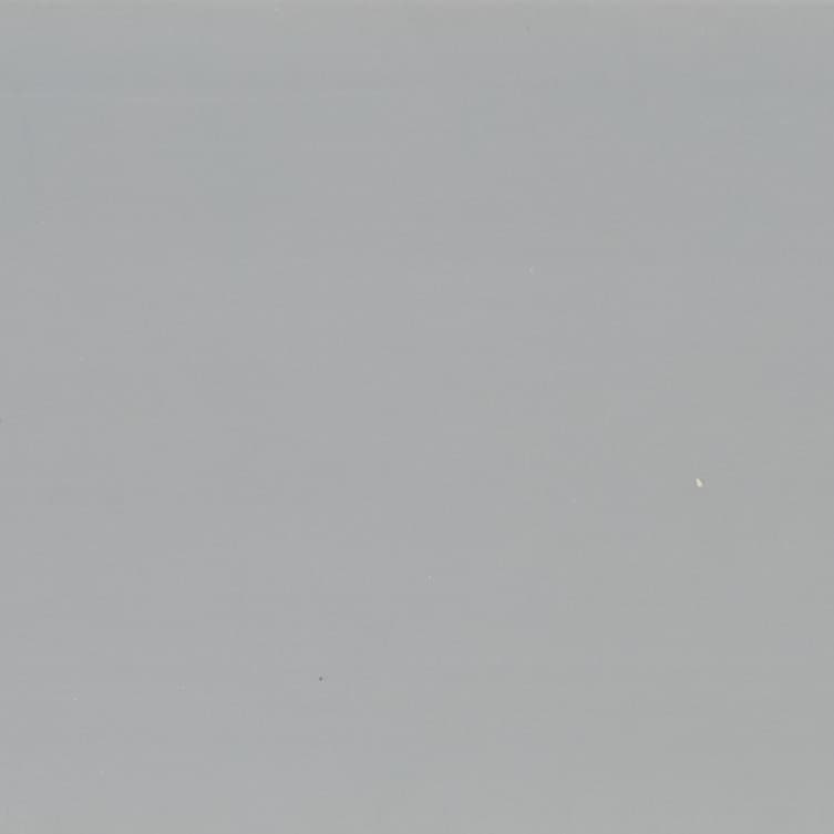 Large smooth matte gray surface with scattered tiny white specks; uniformly lit and stationary; fills frame, suggesting a neutral wall or overcast sky with soft ambient lighting.