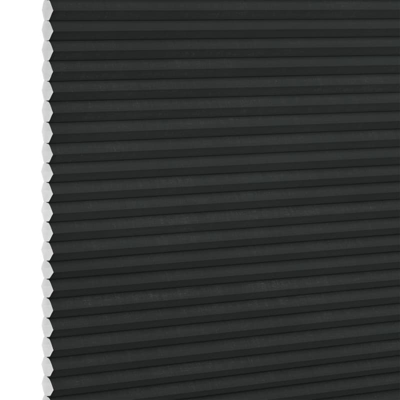 Black honeycomb (cellular) blind, fully lowered and closed with visible white hexagonal cell ends at left, blocking light; close-up interior view with neutral lighting.