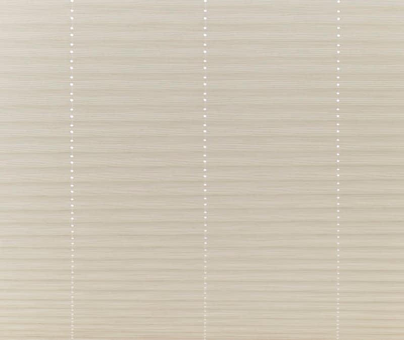 Beige horizontal cellular shades, fully closed with three vertical beadâ€‘chain lines of small white dots; filtering soft daylight into a neutral interior, eliminating any outside view.