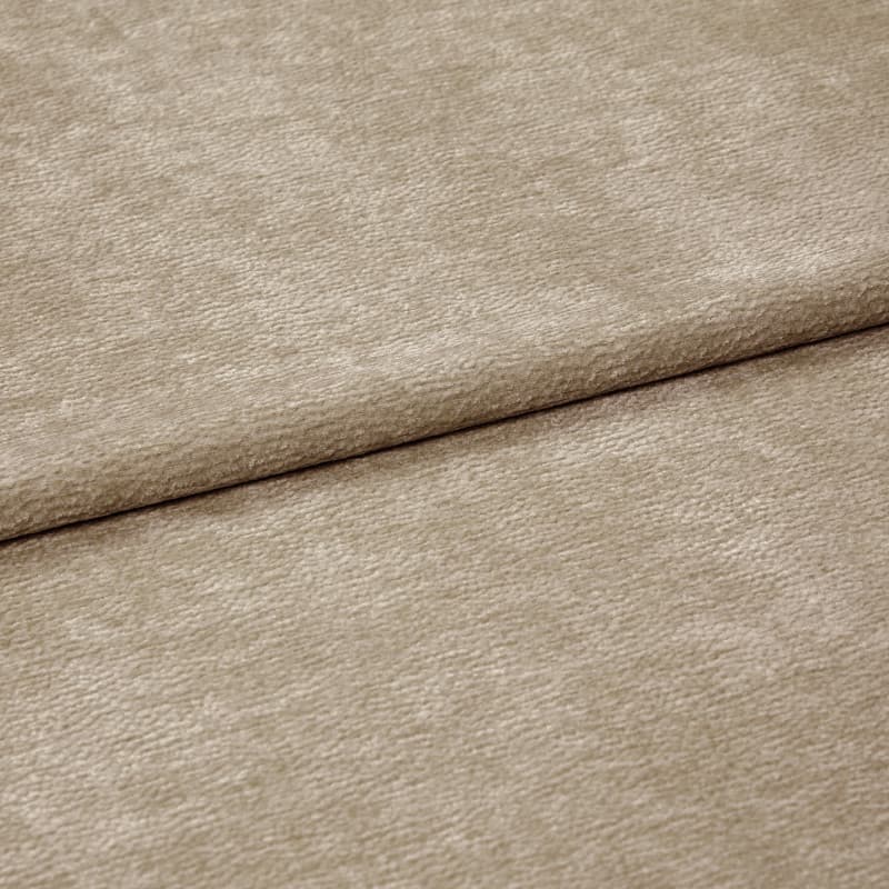 Beige textured fabric folded diagonally, overlapping along a soft crease â€” close-up of a chenille-like upholstery or curtain textile with subtle ribbed pile, even neutral lighting on a flat surface.