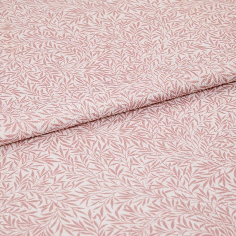 Pink-and-white patterned fabric (leaf print) folded in half and overlapping; close-up flat lay on a neutral surface with soft, even lighting, highlighting woven texture and repeating botanical motif.