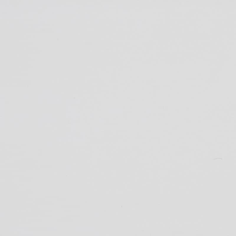 Blank off-white surface shows faint scuffs and tiny specks, evenly lit in a close-up, minimal context with subtle paper- or plaster-like texture.