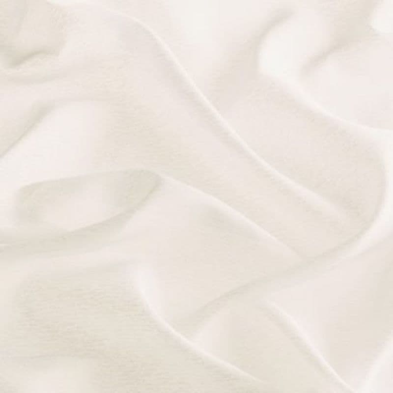 A soft off-white fabric sheet with gentle folds and shallow depressions; rumpled and draped, creating subtle shadows â€” close-up under diffuse, warm lighting against a neutral background.