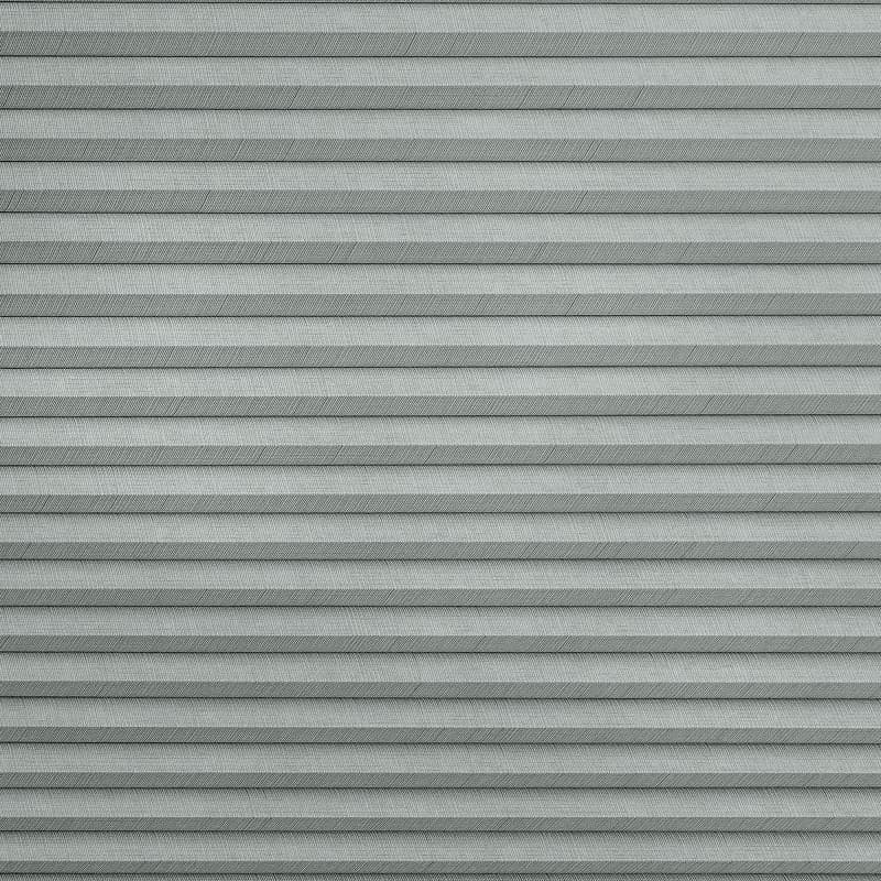 Gray horizontal pleated fabric blinds with subtle herringbone texture; fully closed, filtering soft light; fills the frame, neutral indoor lighting, no surrounding room details visible.