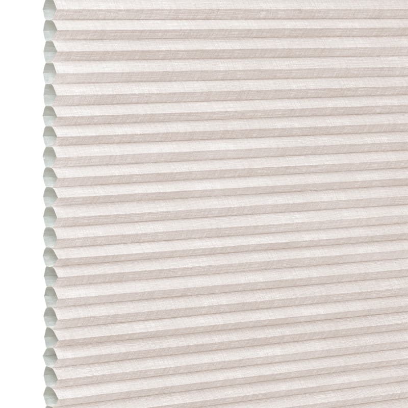 Beige pleated cellular (honeycomb) shade, horizontal ridges with visible open cells at left edge; fully lowered and closed, softly diffusing daylight in a neutral, featureless interior close-up.