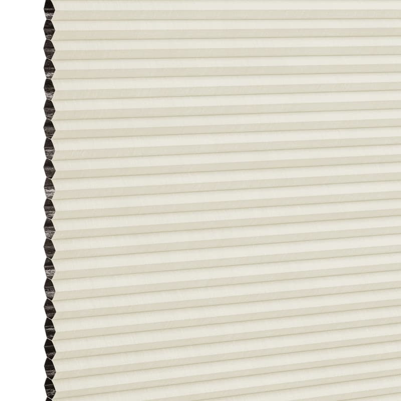 Cream cellular (honeycomb) blind with dark-lined cells visible on the left; closed into uniform horizontal pleats, filtering soft diffuse indoor light against a neutral background.