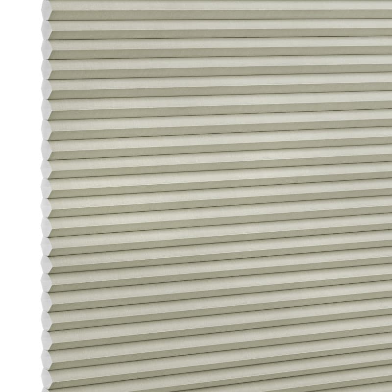 Beige honeycomb (cellular) blind with horizontal pleats and visible hexagonal cell ends at left, fully lowered and closed, blocking light; close-up filling the frame against a neutral, studio-lit background.