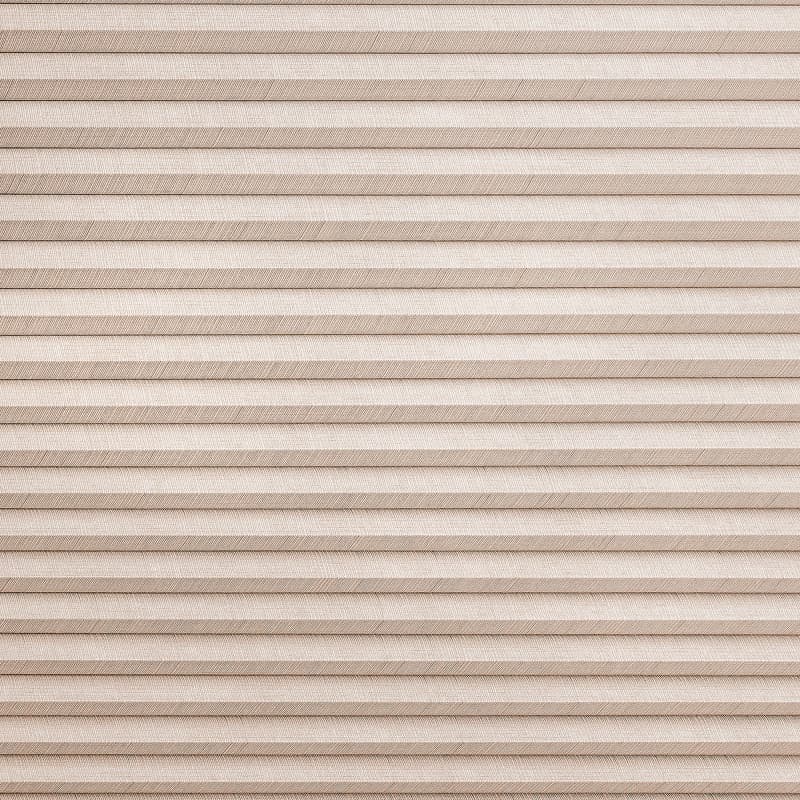 Beige pleated cellular shades covering a window, fully lowered and closed; textured horizontal folds diffuse incoming light, creating an evenly lit, neutral interior surface.