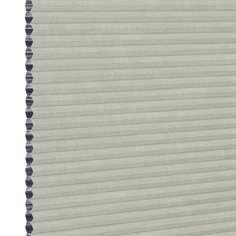 A closed light-gray cellular (honeycomb) window shade, hexagonal dark-gray cell edges visible along the left; filtering light while covering the opening; close-up view with neutral, even lighting.