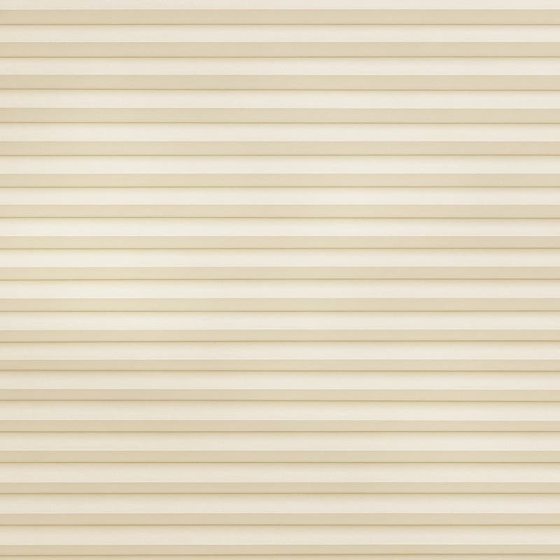 Beige pleated cellular blind, stretched across the frame; fully lowered and closed, softly diffusing light in a neutral, softly lit interior with no visible view.