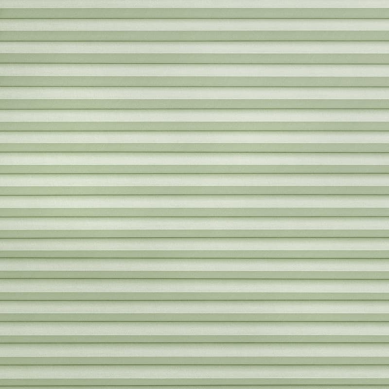 Light green pleated cellular shades spanning the frame, fully lowered and closed with horizontal ribbed texture, softly filtering diffuse daylight into a neutral, softly lit interior.