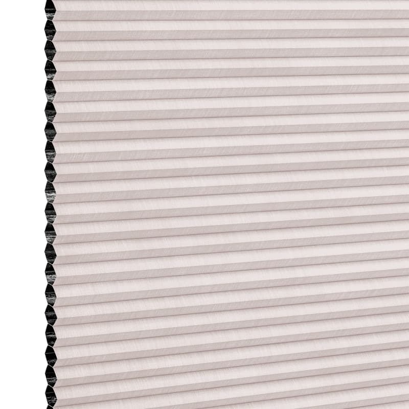Cellular pleated window shade (honeycomb design) fully lowered, pale blush fabric with visible black cell openings at left edge, blocking light; close-up view against a neutral background.