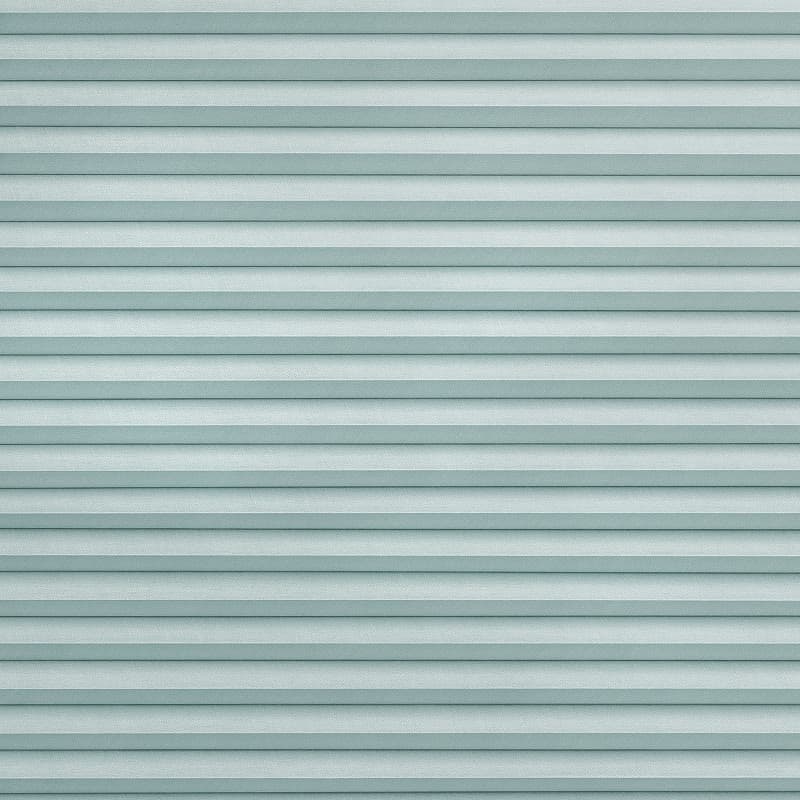 Light-teal pleated cellular blinds covering entire frame, horizontal narrow folds and textured fabric; closed, evenly filtering diffuse cool light; minimal interior context, no visible window or furnishings.
