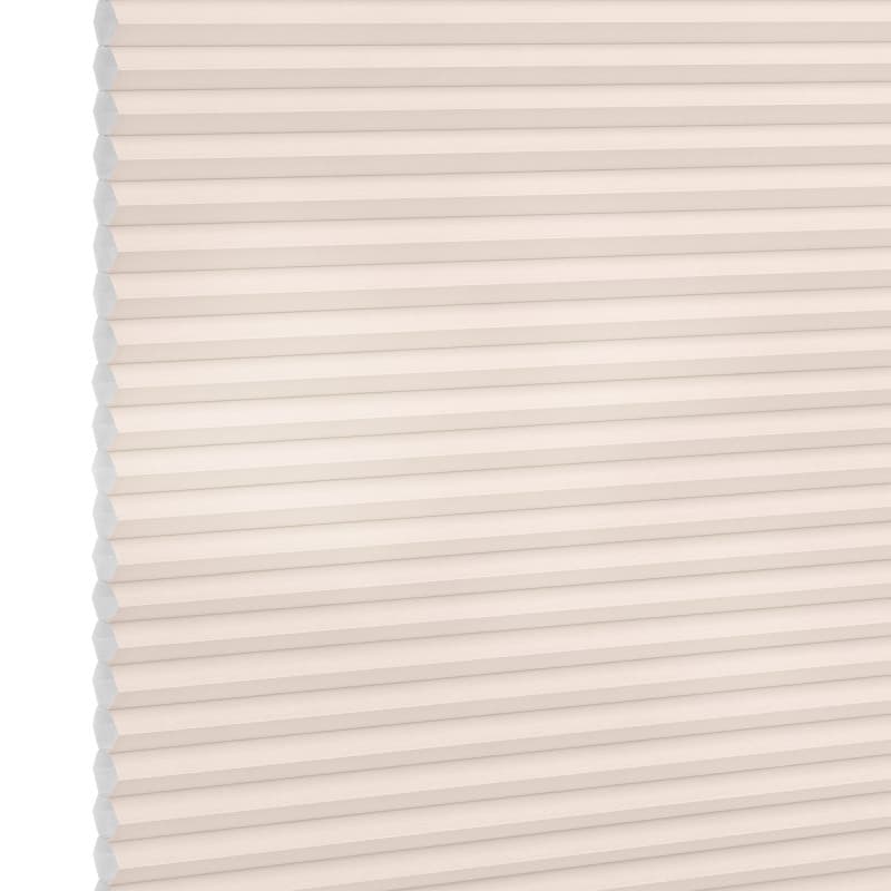 Cellular (honeycomb) pleated blind, cream-colored, fully lowered and closed with visible hexagonal cells; diffusing soft light across a plain interior wall, suggesting a bright, neutral room.