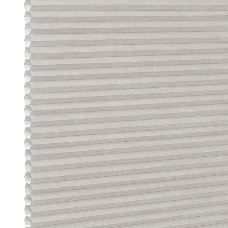 White pleated honeycomb (cellular) blind, fully lowered with visible hexagonal cells at left edge, closed and softly filtering light, close-up interior view with neutral lighting.