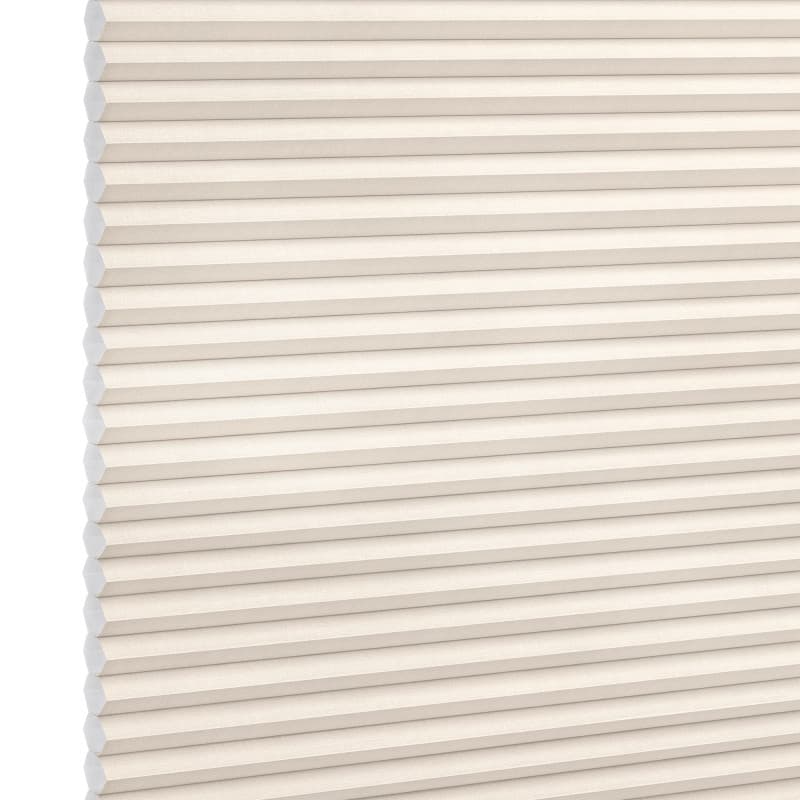 Cream honeycomb (cellular) window shade with horizontal pleats and visible hexagonal cells, fully lowered and closed, softly diffusing light; photographed as a studio product shot with neutral background.