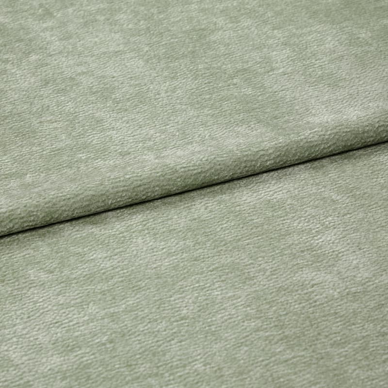 Velvet-like pale sage-green fabric folded horizontally, creating an overlapping seam; soft, short-pile texture; close-up, evenly lit studio view filling the frame.