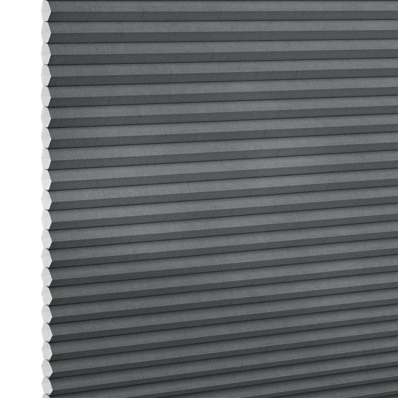 Gray cellular (honeycomb) blind, fully lowered with horizontal pleats and exposed honeycomb edges at left, blocking light; close-up studio view against a white background.