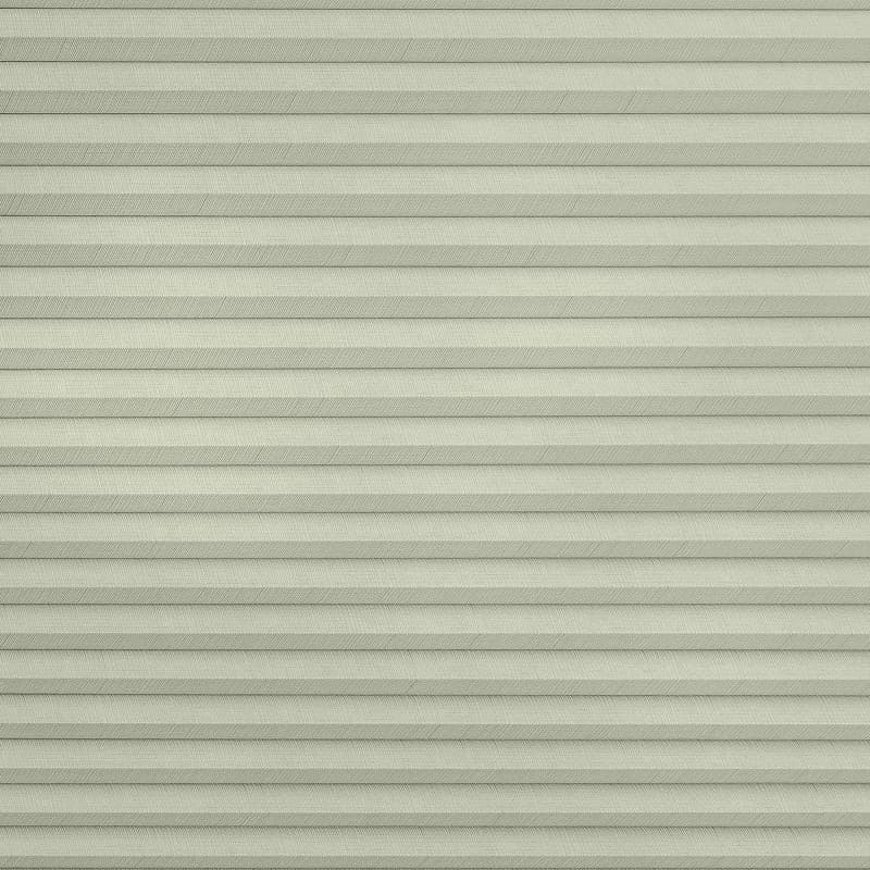 Pleated cellular window shade, fully lowered with uniform horizontal pleats and subtle herringbone fabric texture; closed to block view and softly diffuse daylight across a pale, neutral interior surface.