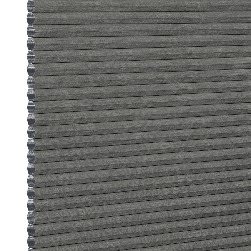 Gray honeycomb (cellular) fabric blind, fully lowered with visible hexagonal cells along the left edge; blocking light, shown in an even, neutral close-up product background.