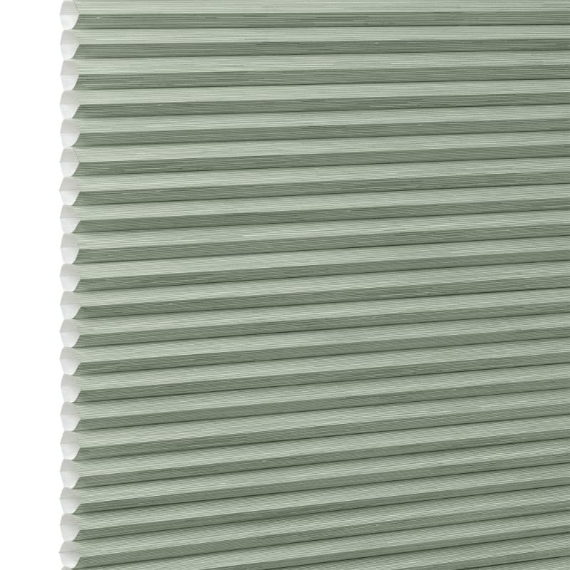 Honeycomb cellular blind with horizontal pleats and white cell edges â€” fully lowered and closed â€” pale sage-green fabric, close-up interior view, evenly lit and diffusing incoming light.