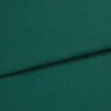A folded teal-green woven fabric (linen texture) lies overlapping, the top edge forming a horizontal fold; close-up studio shot with even lighting and no visible background.