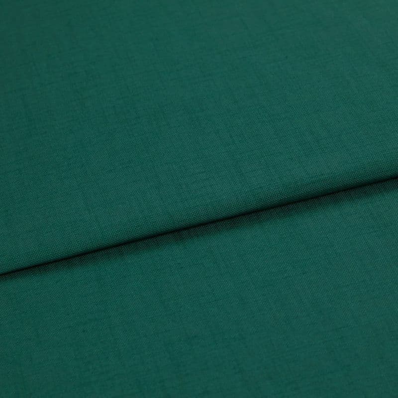 A folded teal-green woven fabric (linen texture) lies overlapping, the top edge forming a horizontal fold; close-up studio shot with even lighting and no visible background.