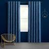 Blue grommet curtains, marbled swirl, hung on a rod and parted to frame a central window; filtering daylight; dark-blue room with a gold wire chair and circular wall décor.