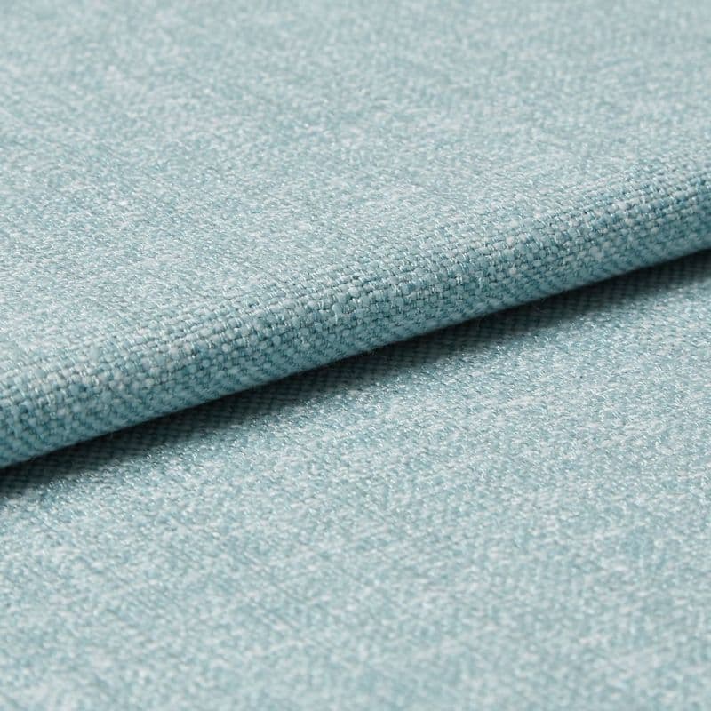 Light-blue woven upholstery fabric folded so one edge overlaps, revealing tight textured weave; photographed as a close-up on a flat surface with soft, even studio lighting for a material sample.