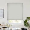 White cellular blind (honeycomb), lowered with horizontal pleats and slight lift at bottom, filtering daylight; over a window in a bright minimalist dining area with table, vase, and potted plant.