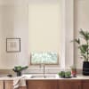 Beige roller blind covers most of a kitchen window, blocking light and revealing a narrow view; below, faucet and sink sit on a countertop with bowls, potted plants, towel.