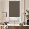 Roller blind covers the upper portion of a kitchen window, blocking light; stainless faucet and double sink sit below on a countertop with plants, vegetables, towel and wooden cabinets.