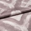 Soft woven fabric with faded mauve geometric frames and subtle heart motif (folded across the center), draped and overlapped to reveal stitched texture, close-up under even studio lighting.