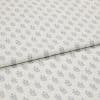 Light-coloured cotton fabric with repeating small grey leaf motifs, folded across the middle, shown in a soft, evenly lit studio close-up.