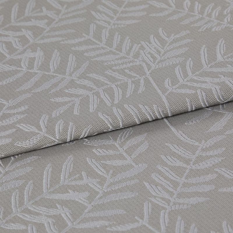 Beige-gray woven fabric with raised white botanical leaf pattern, folded once and layered, displaying texture and subtle sheen; close-up on textile surface under soft, neutral lighting.