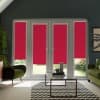 French patio doors with four red roller blinds covering the lower thirds, framed by dark gray walls; two green armchairs, a glass coffee table on a chevron rug, and a garden outside.