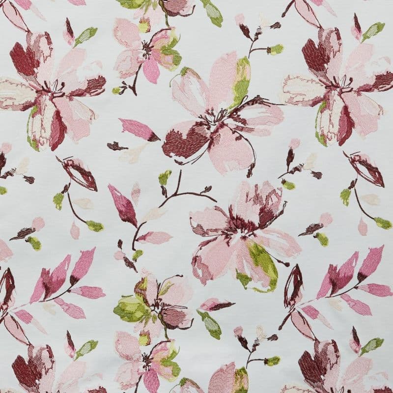 Floral fabric with large embroidered-style pink, burgundy, and green blossoms and buds — repeating pattern scattered across the surface — flat, evenly lit white background.