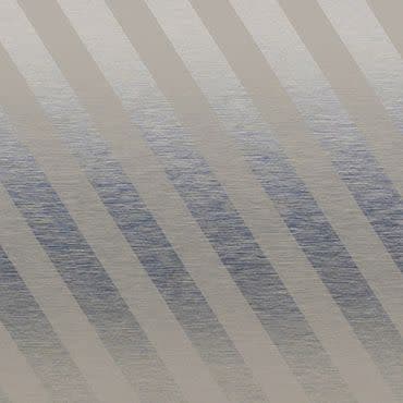 Diagonal-striped fabric window blind across the frame, alternating opaque beige and semi-translucent gray bands; filtering daylight and casting muted banded shadows; softly lit interior with a subtle textured surface visible behind.