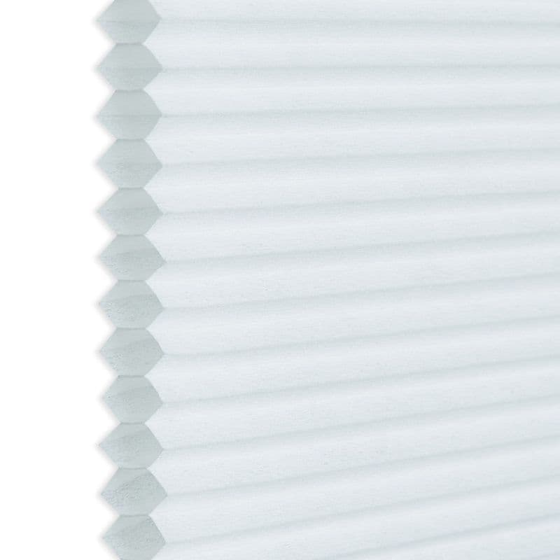 White honeycomb (cellular) blind, hexagonal pleats visible along the left edge; closed and diffusing light; photographed close-up against a neutral background, showing even soft daylight and subtle texture.
