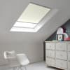 Room with white eaves wall, dark blue-grey wall to right with a shabby chic white drawer unit, a contemporary white chair, white painted floorboards and a skylight blind in cream.