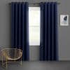Navy grommet-top blackout curtains, two panels hung on a metal rod, parted slightly to reveal a bright single-pane window; minimalist living space with gray walls, gold wire chair, soft daylight.