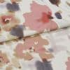 Folded floral-patterned fabric panel — watercolor-style pink, mauve and gray blooms on a pale background — overlapping fold across center, close-up view under soft, diffuse lighting.