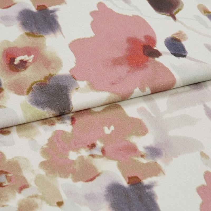 Folded floral-patterned fabric panel — watercolor-style pink, mauve and gray blooms on a pale background — overlapping fold across center, close-up view under soft, diffuse lighting.