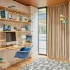 Beige pleated floor-to-ceiling curtains drawn closed, softly filtering daylight; they cover a tall glass door beside a wooden-shelved home office with a desk, blue chair, computer, patterned rug.
DESIGN
Palm Springs Weekend