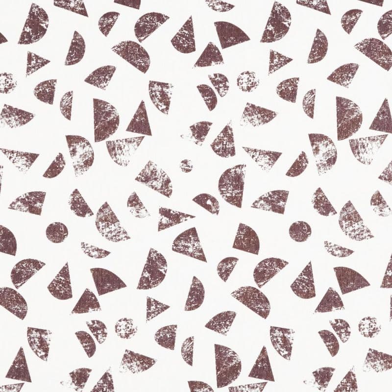 Distressed brown geometric shapes (half-circles, triangles, circles) stamped repeatedly—scattered across a white background—creating a loose, random repeating pattern with worn, textured prints.