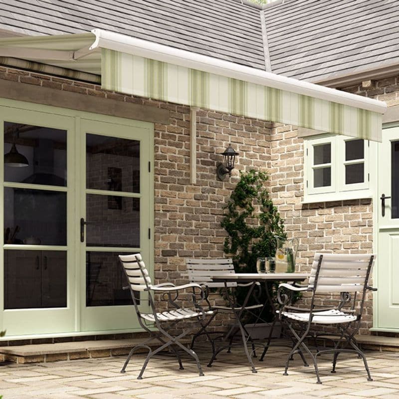 Striped green-and-white retractable awning extended from the roof, shading and softly filtering light over a brick-walled patio with mint-green French doors, a bistro table and chairs, and a potted climber.