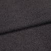 Dark charcoal looped fabric, forming a shallow horizontal fold, close-up studio view emphasizing coarse, pebble-like texture under even, neutral lighting.