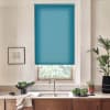 Turquoise roller blind partially covers a window, blocking light; below it a sink and faucet sit on a countertop with bowls of vegetables, a towel, and potted plants in a modern kitchen.