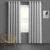 Light-gray grommet-top curtains flank a central window, partially closed and filtering soft daylight; gray-walled minimalist room with a gold wire chair and small abstract wall art, faint greenery outside.