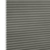 Grey honeycomb (cellular) pleated blind, vertically positioned with visible hexagonal cells at left edge; lowered and closed, evenly blocking light in a close-up, neutral studio-lit view.